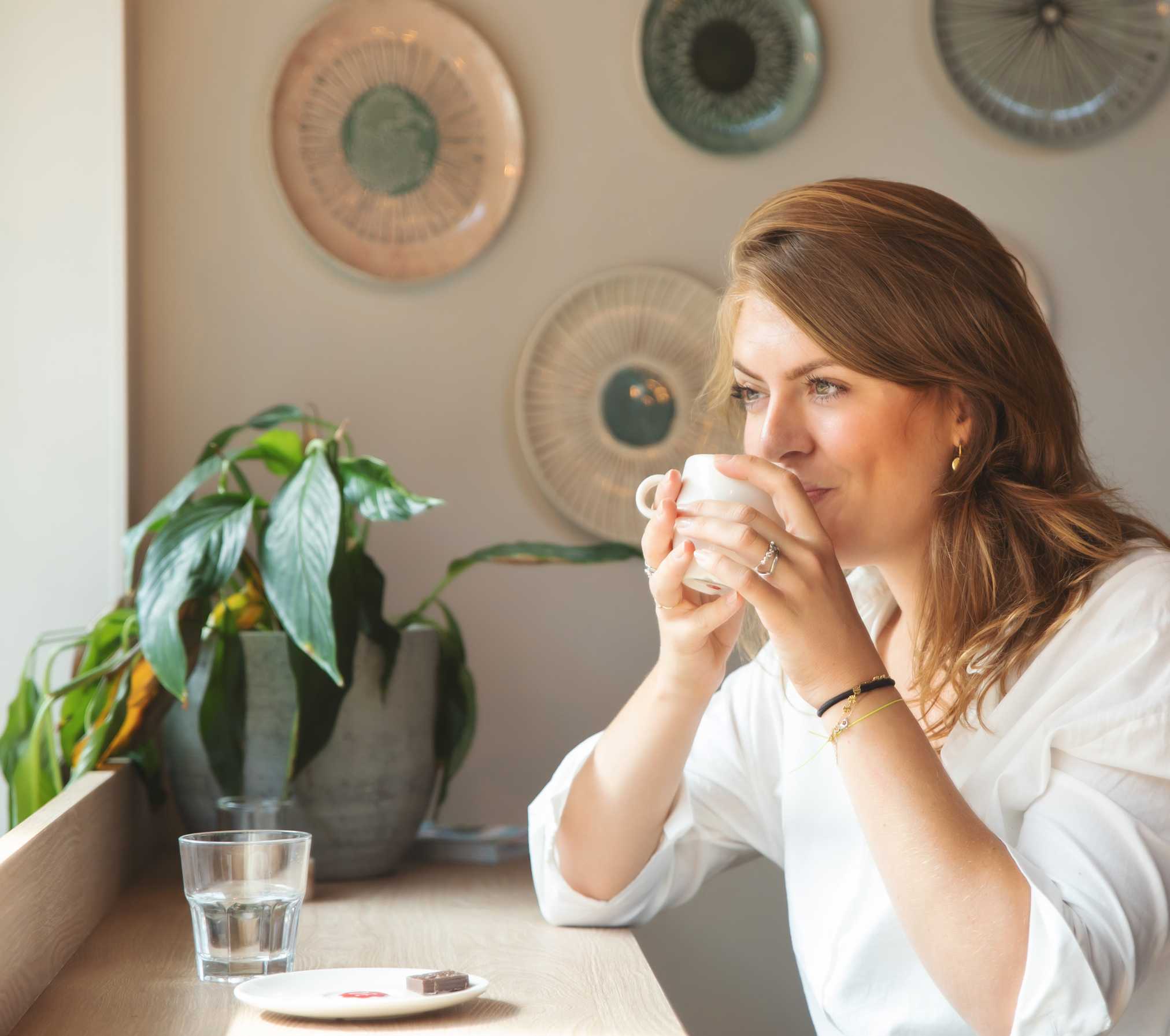 A woman enjoying a cup of coffee in a café while showing resilience and building team development.