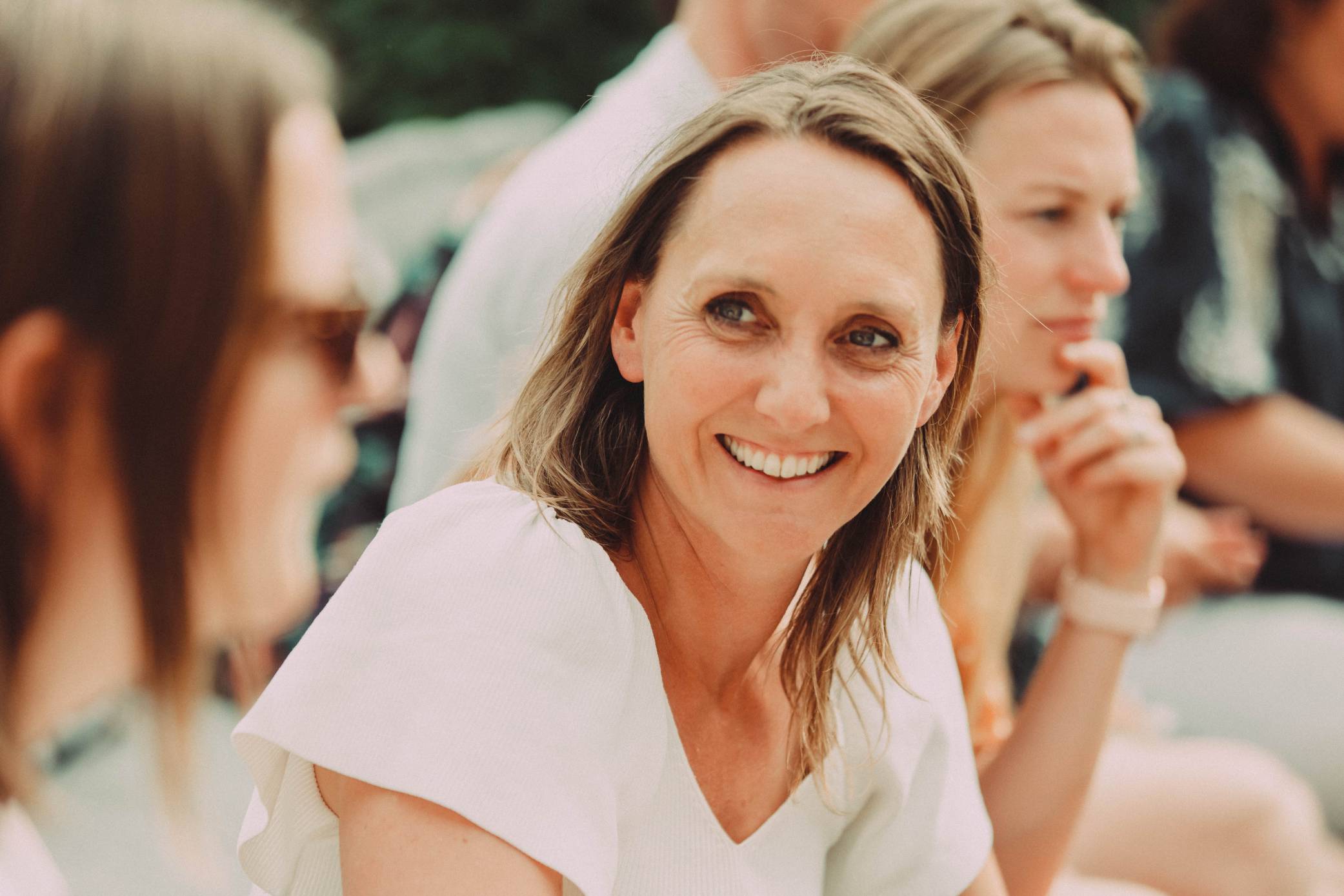 A resilient woman smiles as she sits in a group of people during a team development training.
