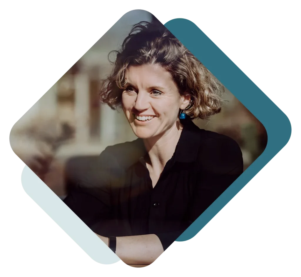 Een glimlachende vrouw met krullend haar, gekleed in een zwarte blouse en blauwe oorbellen, is omlijst door een gestileerde geometrische rand die licht reflecteert.